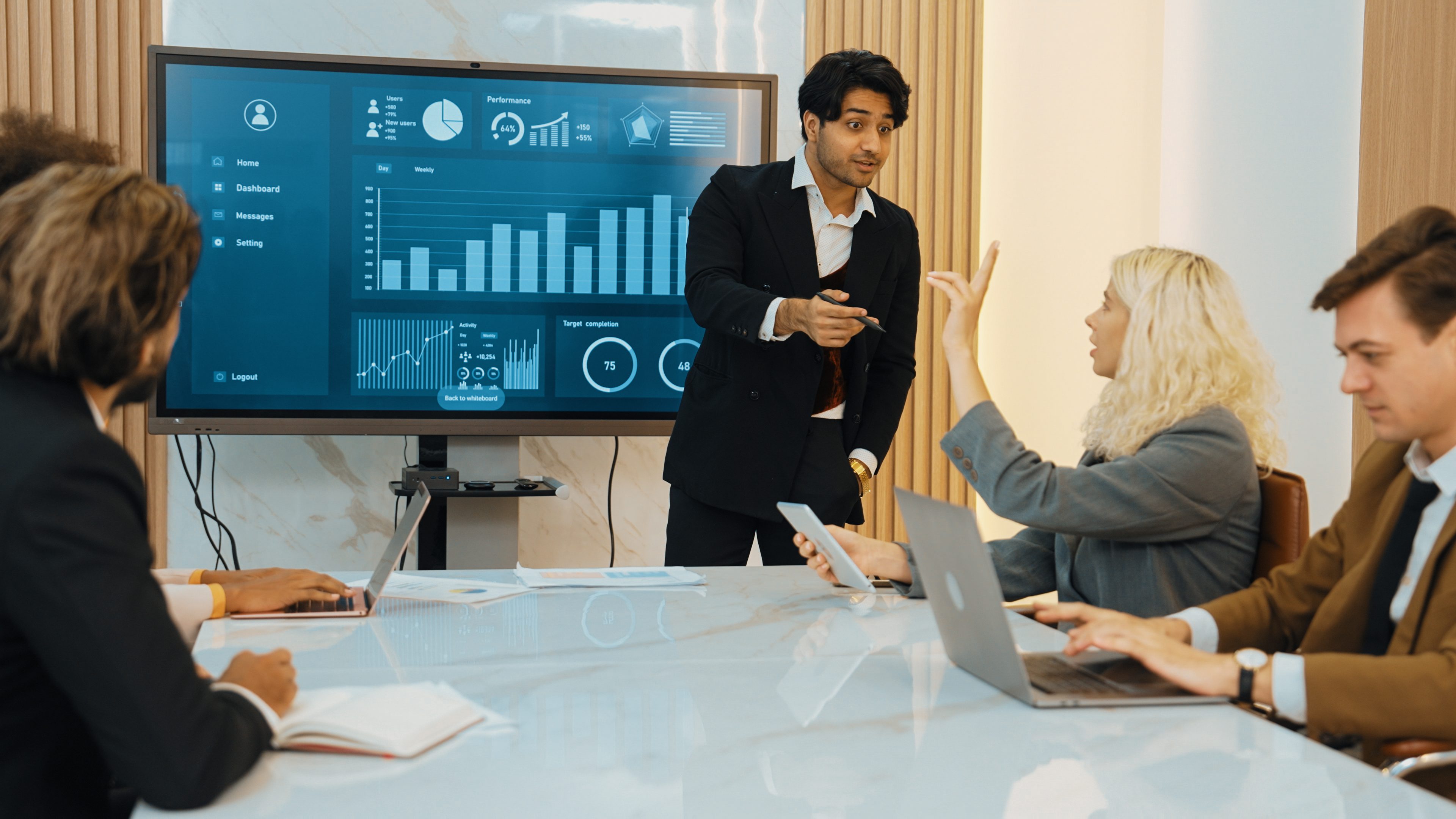 A man presenting financial data to colleagues in a meeting room.