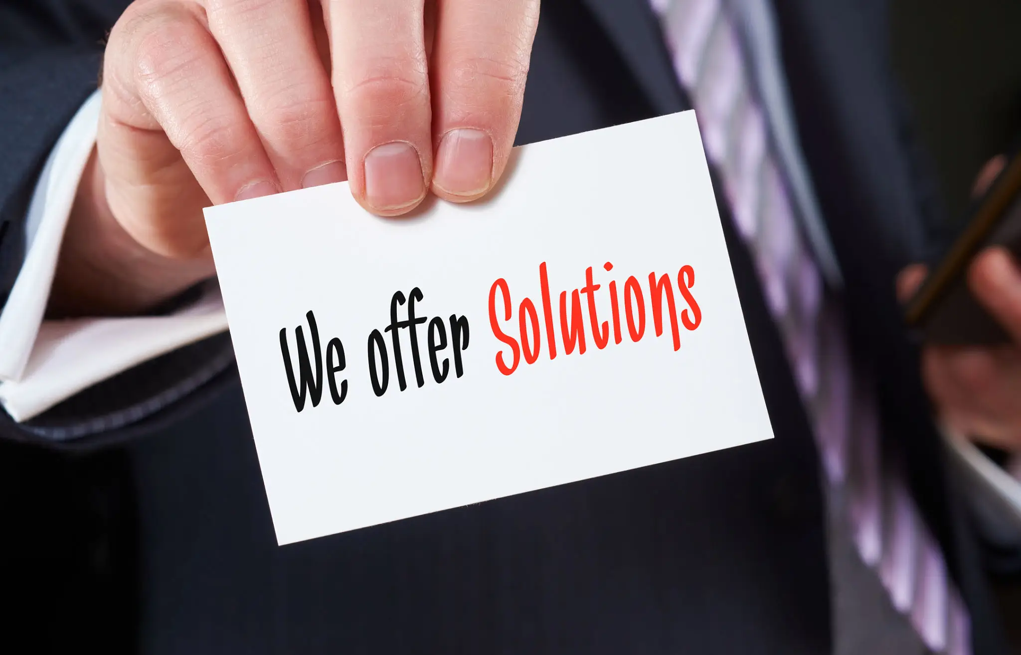 A hand holding a card saying 'We offer solutions' with emphasis on solutions.