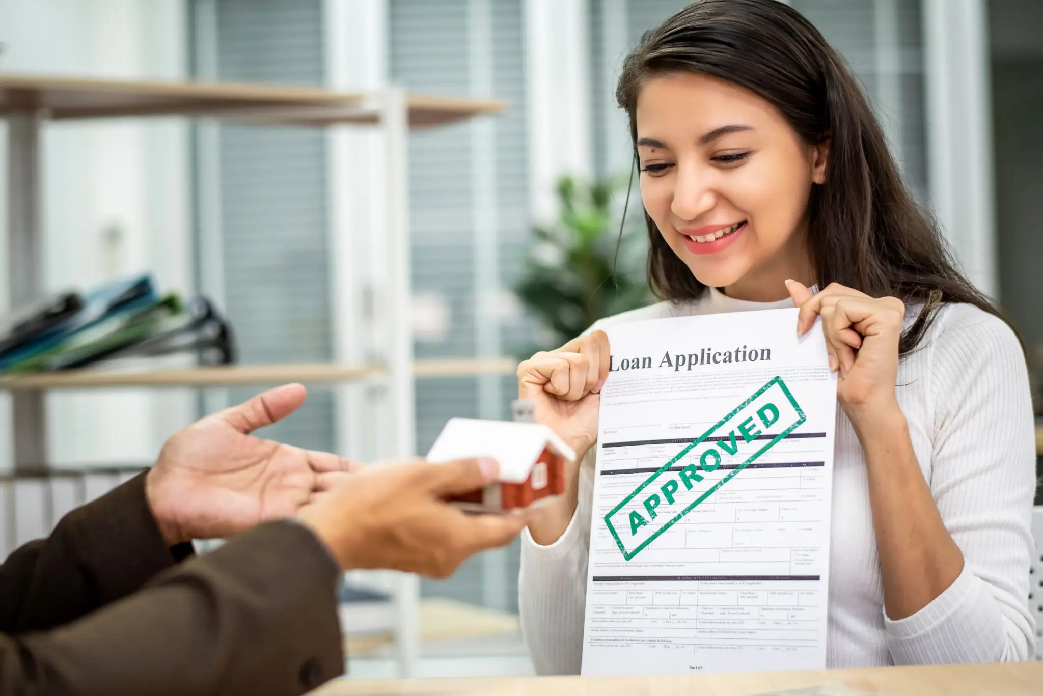 Happy woman holding an approved loan application.