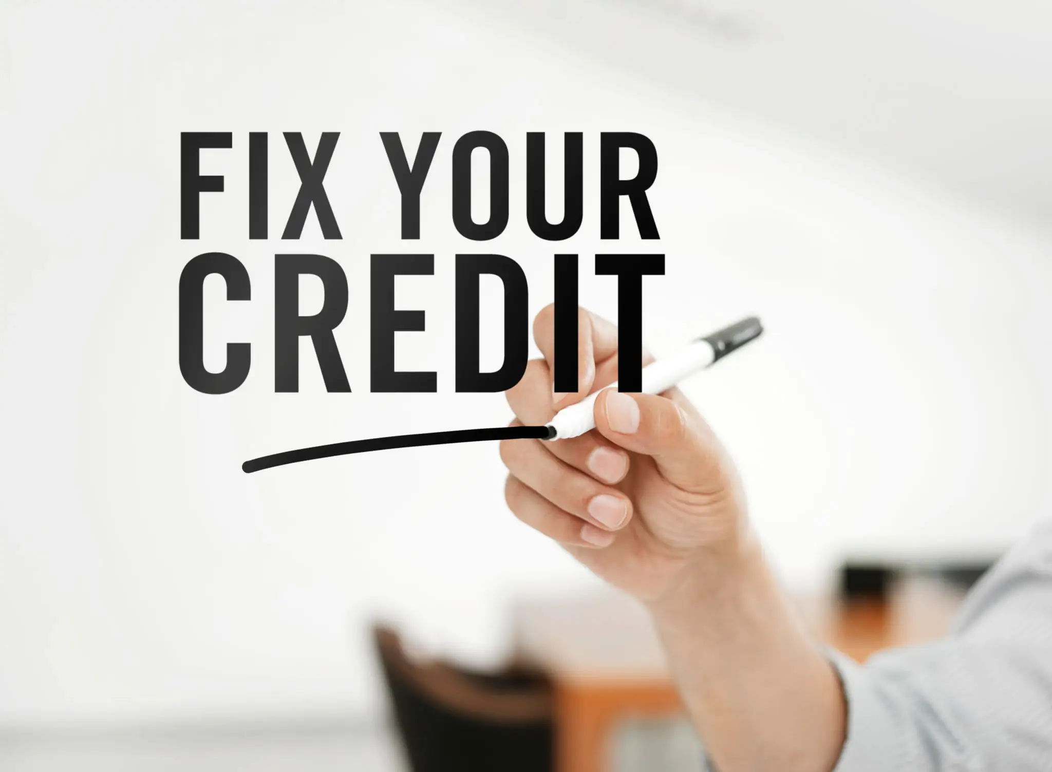 Hand writing 'Fix Your Credit' on a transparent board.